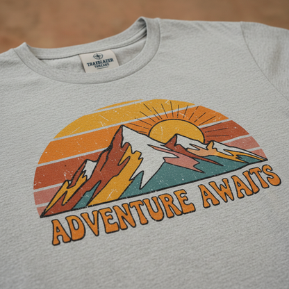 Close-up of retro adventure t-shirt showing vintage sunset colors and mountain design
